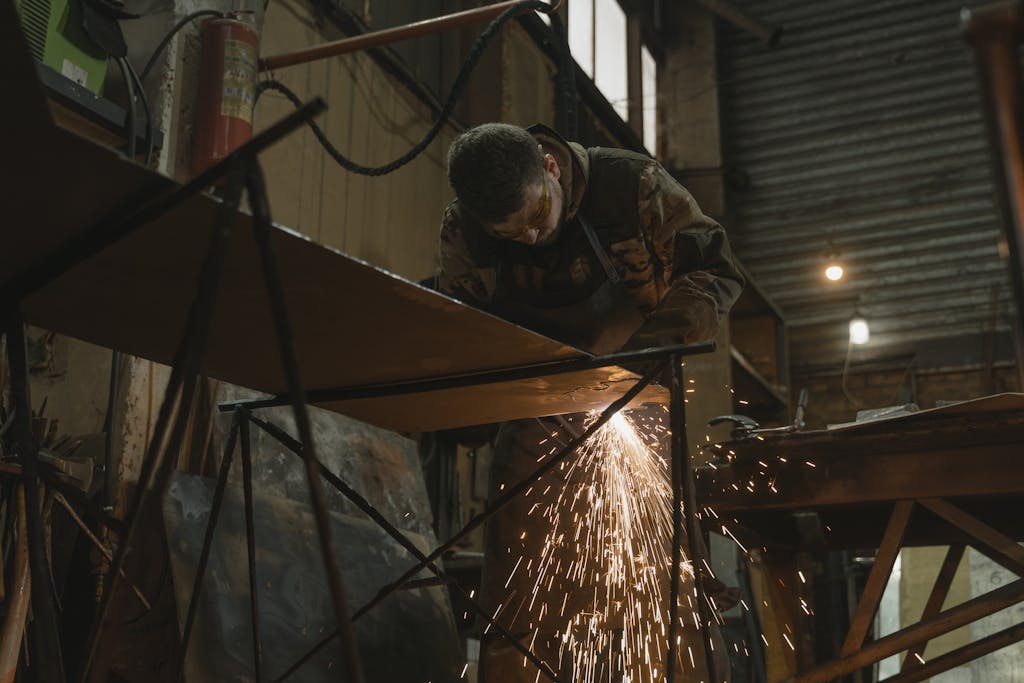 Fabrication A worker focused on welding metal inside an industrial setting with sparks flying.