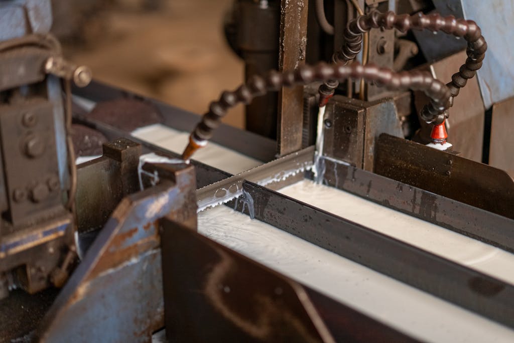 Optimiseur decoupe tube Close-up view of an industrial metal cutting machine in operation with coolant flowing.