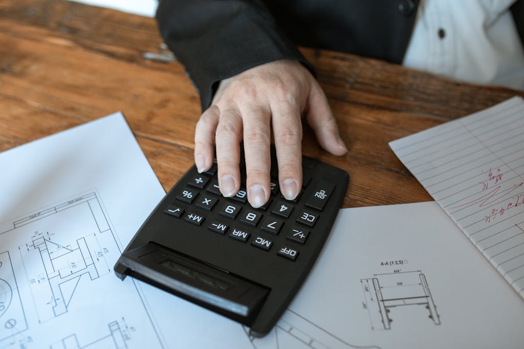 Devis Hand using calculator for architectural calculations on blueprints.