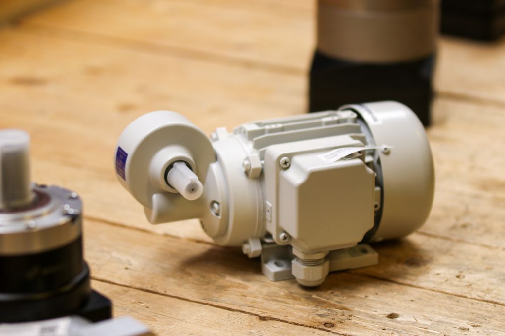clavette Close-up of a white industrial motor placed on a wooden surface inside a workshop.